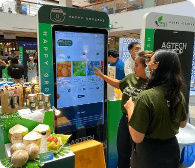 Customer interacting with digital kiosk at Happy Grocers